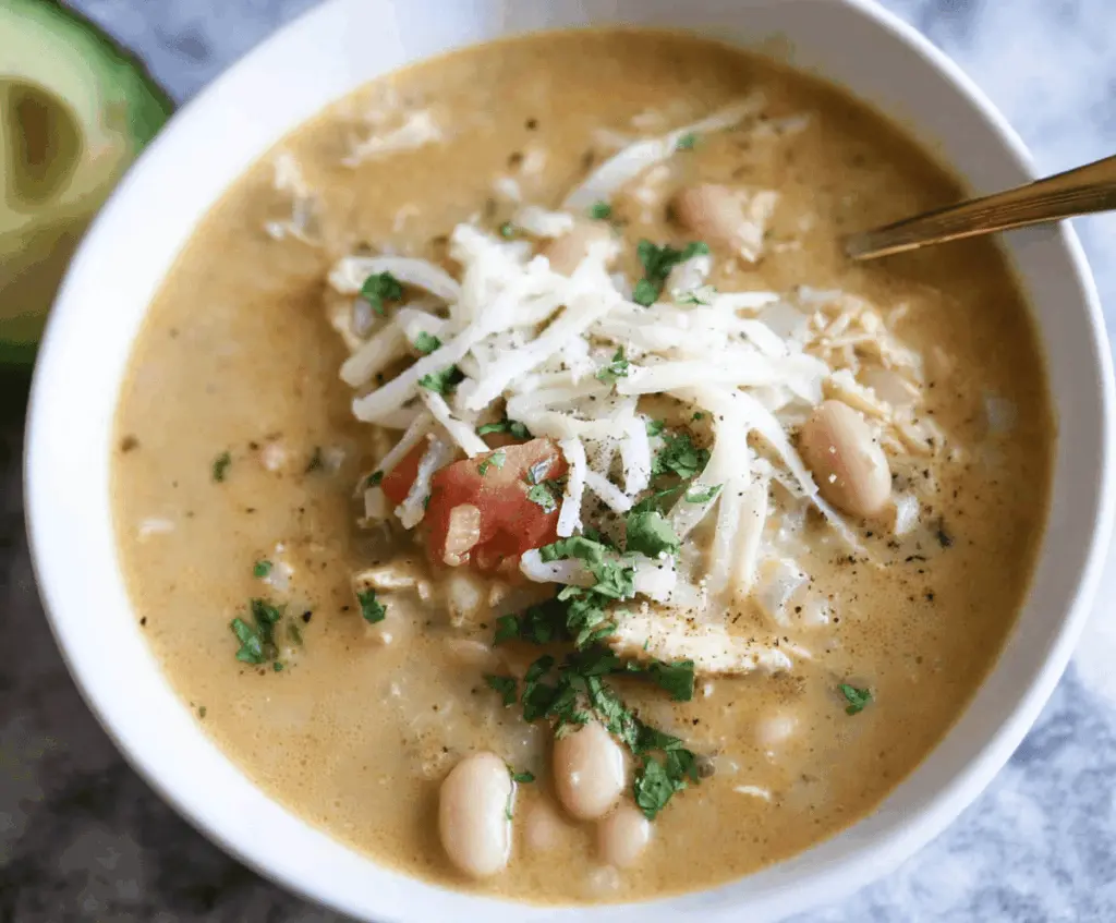 Creamy white bean enchilada soup topped with melted cheese and fresh cilantro in a bowl, served with tortilla chips