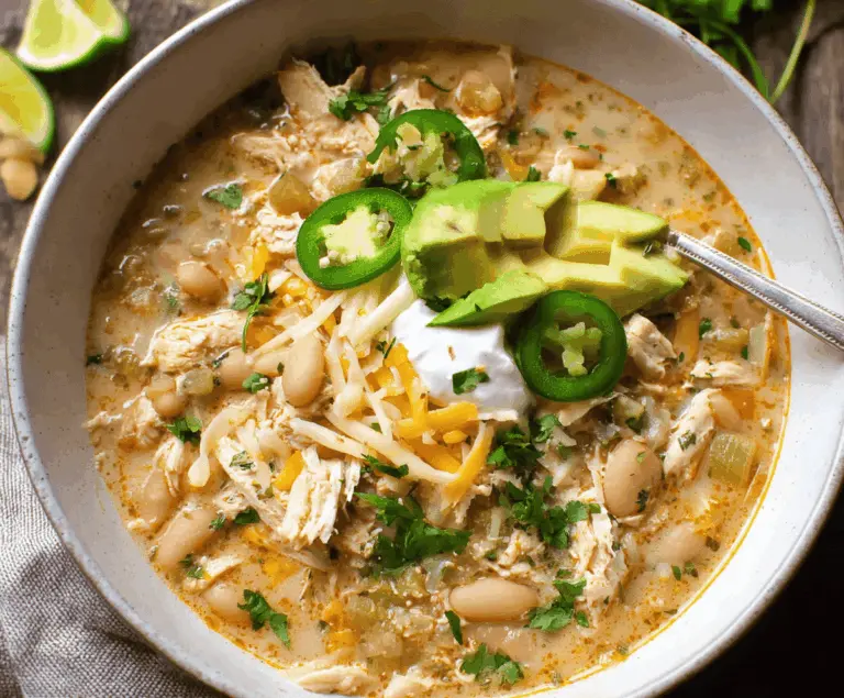 Creamy white chicken chili in a crockpot with tender shredded chicken, white beans, green chilies, and fresh herbs served in a bowl
