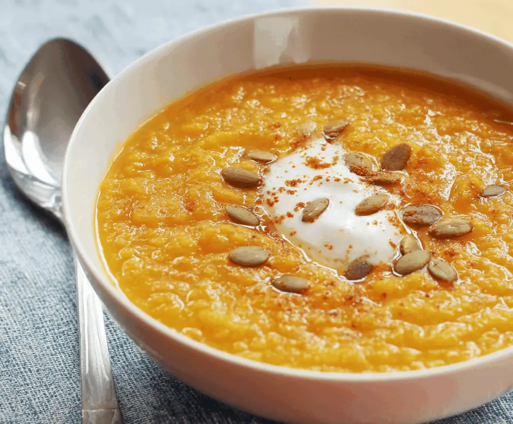 Creamy pumpkin curry soup garnished with fresh herbs in a bowl, perfect for a warm autumn meal