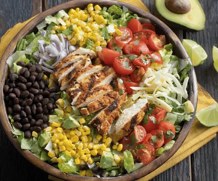 Colorful Southwest Chicken Salad featuring grilled chicken, corn, black beans, cherry tomatoes, avocado slices, shredded cheese, and fresh greens in a vibrant bowl