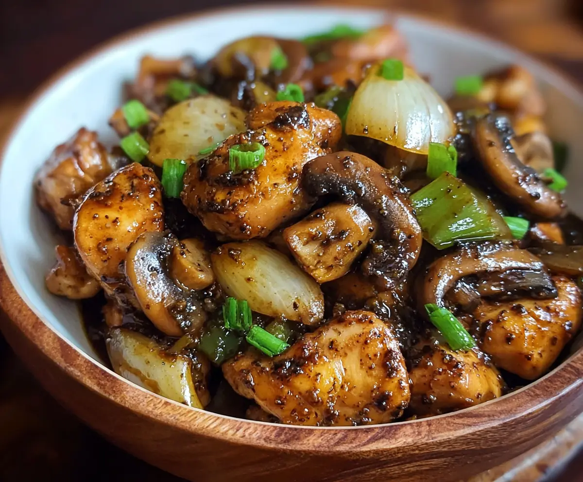 Delicious Black Pepper Chicken with Mushrooms served on a white plate, garnished with fresh herbs.
