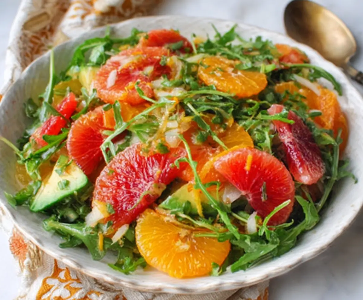 Fresh winter citrus and arugula salad with orange slices, grapefruit, and peppery arugula leaves in a vibrant plate.