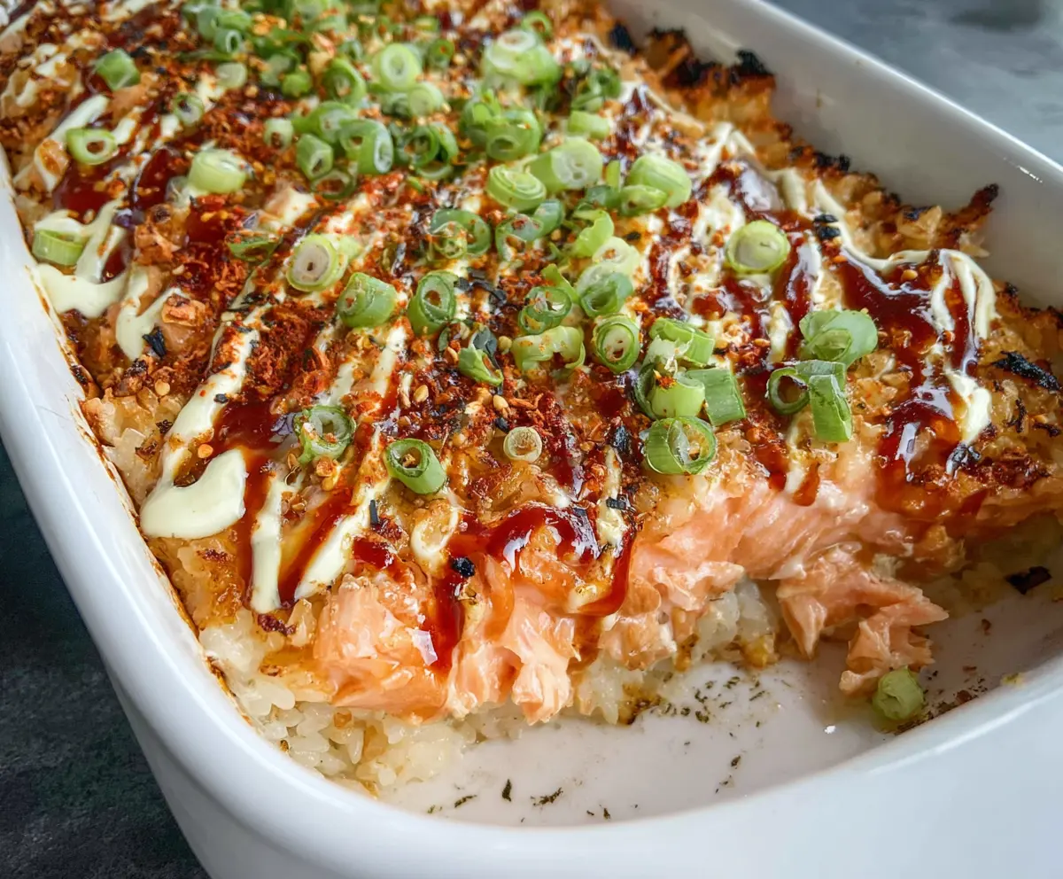 Delicious spicy salmon sushi bake with crispy top, served in a white ceramic dish.