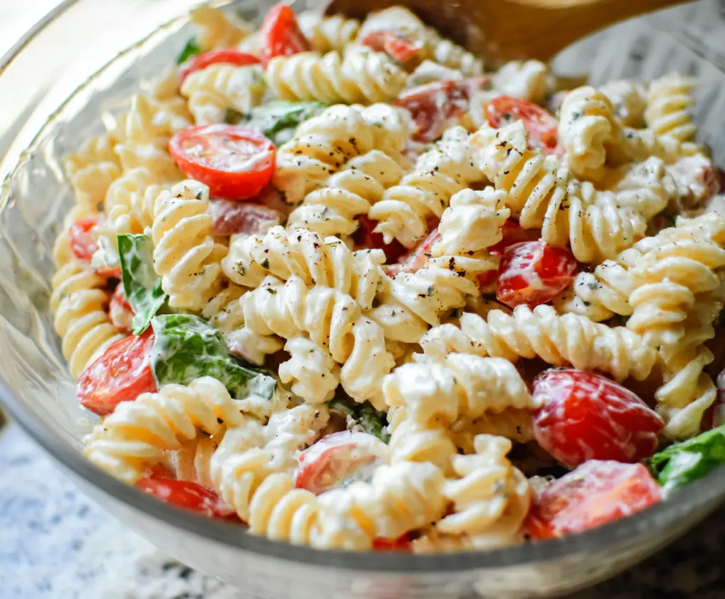 Delicious creamy pasta salad with fresh vegetables and herbs, perfect for summer picnics and barbecues.