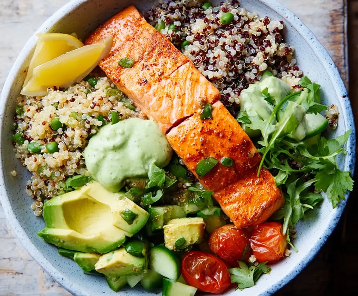 Healthy salmon and quinoa power bowl with fresh vegetables and herbs.